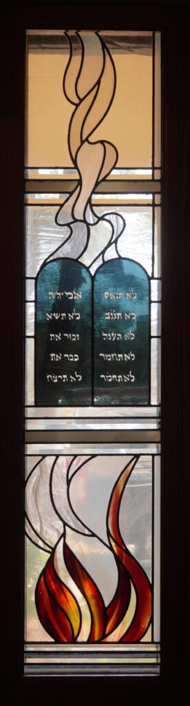 stained glass window of burning tablets with hebrew writing on them above flames. 