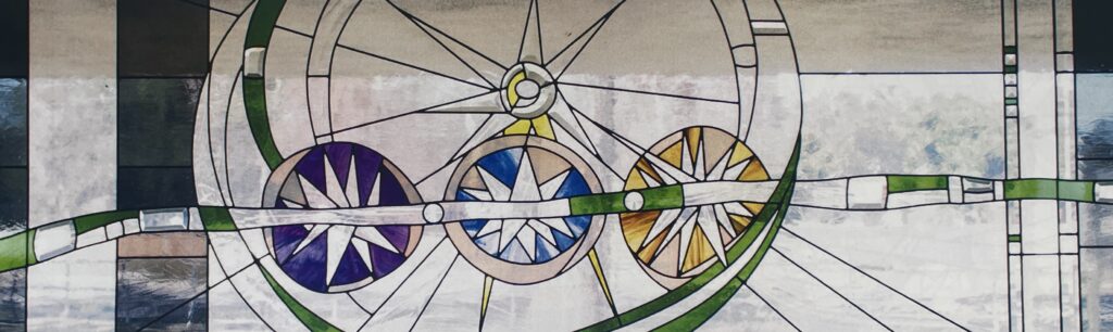 stained glass window with 3 stars in front of a larger star. 