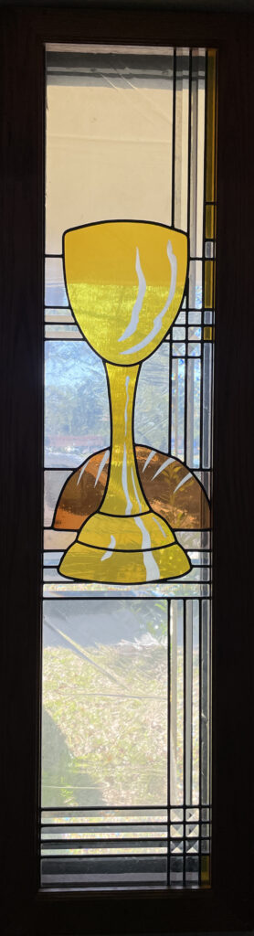stained glass window of gold goblet and loaf of bread.