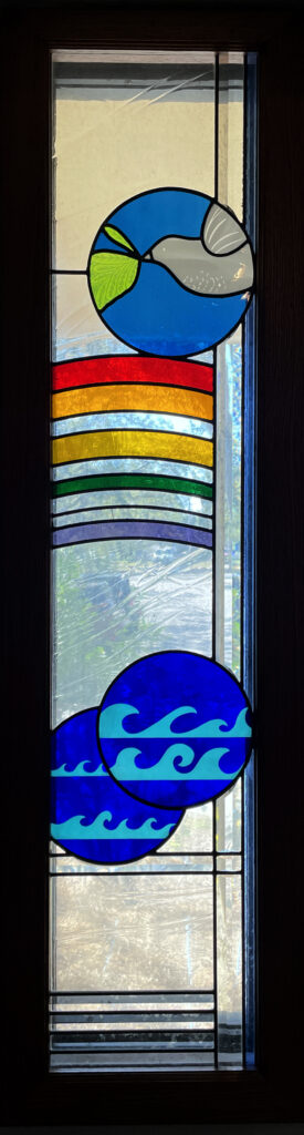 stained glass window of dove carrying branch over a rainbow with water motifs.