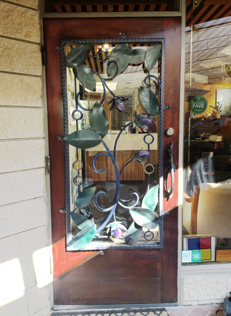 door with metal leaf and flower motifs covering the clear glass. 