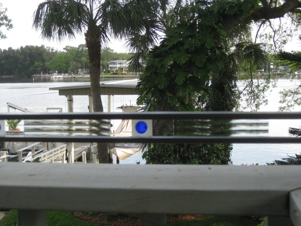 metal railing on deck with small pieces of glass in between the metal bars, blue circles and clear with lines.