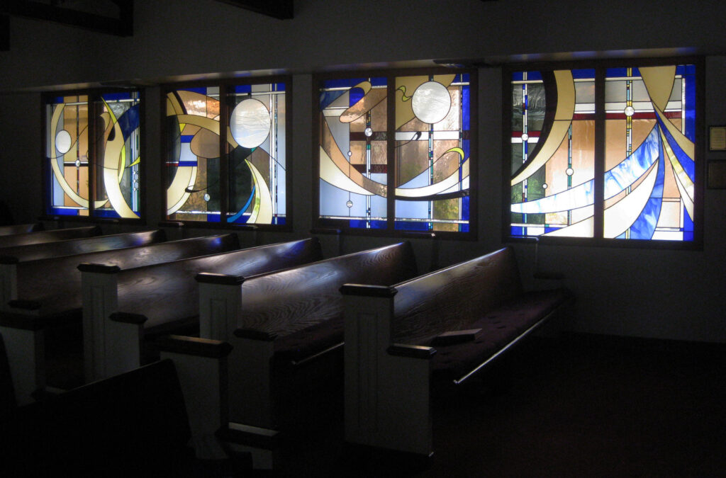 image of chapel with stained glass windows beside wooden pews. 