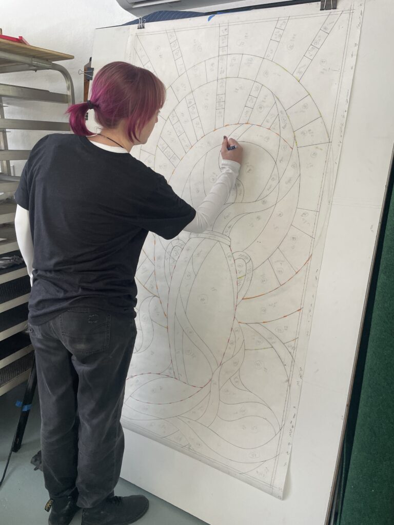 person sketching a stained glass pattern.