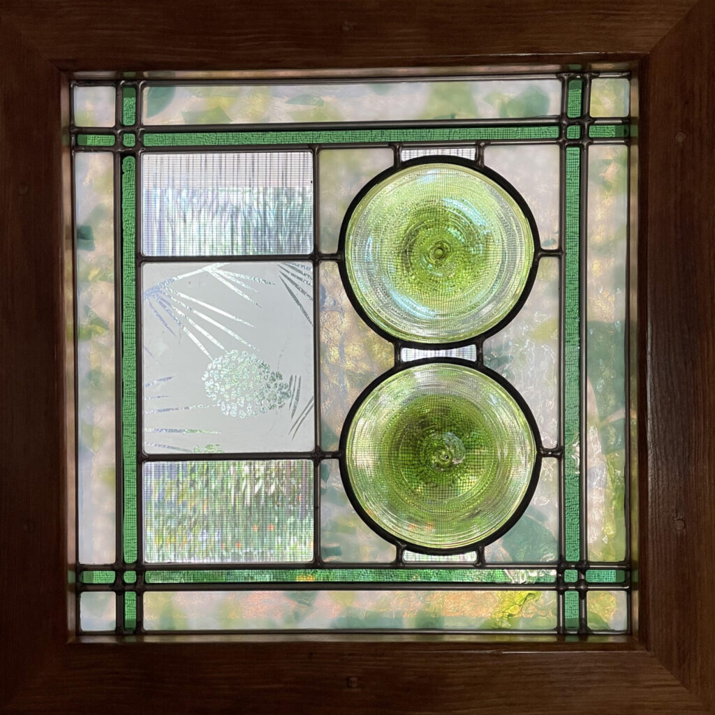 small square front door panel with two green circles and a etched pine cone detail.